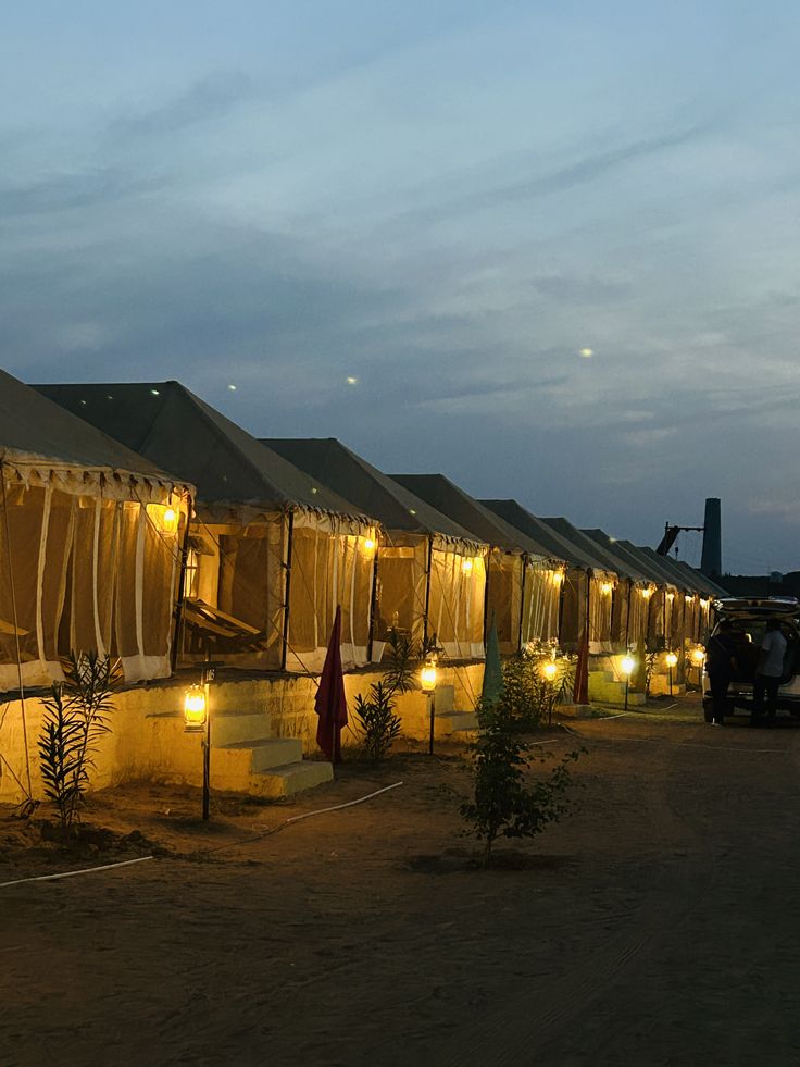 Canvas tents softly lit by lanterns in the desert at blue hour